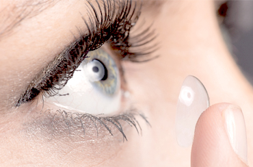 Woman inserting contact lens in eye