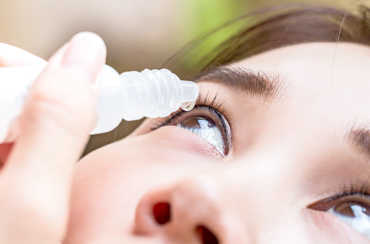Asian woman inserting eye drops